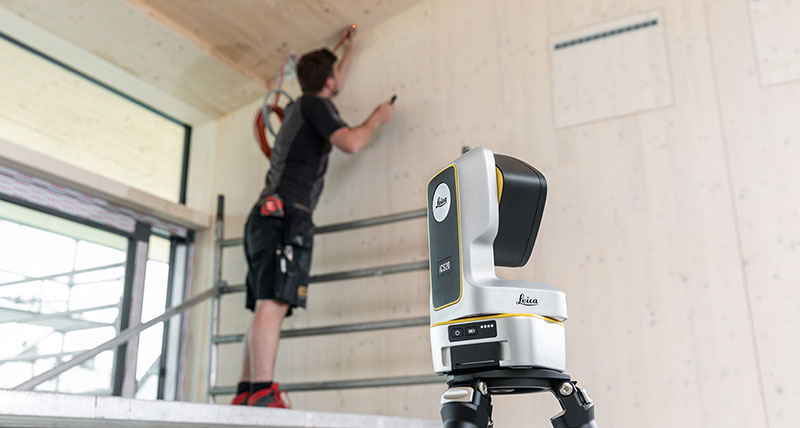 Leica iCON iCS20 used to mark installation points on a wall with worker in dark clothing.